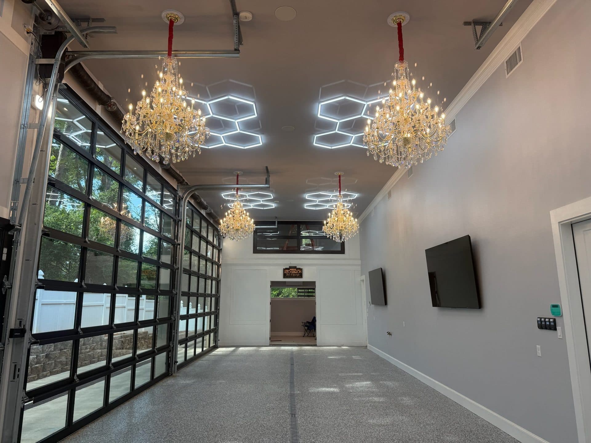 Auto Saloon showroom with glass garage doors, chandeliers, and epoxy floor