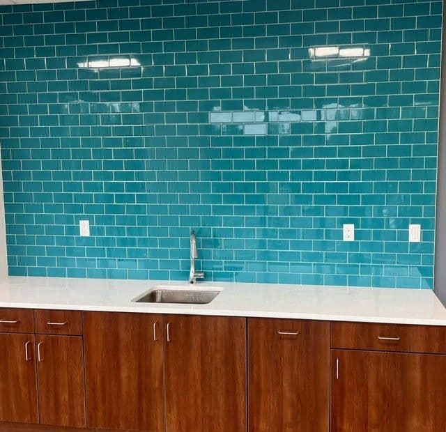 Commercial break room wet bar with teal subway tile and walnut cabinets