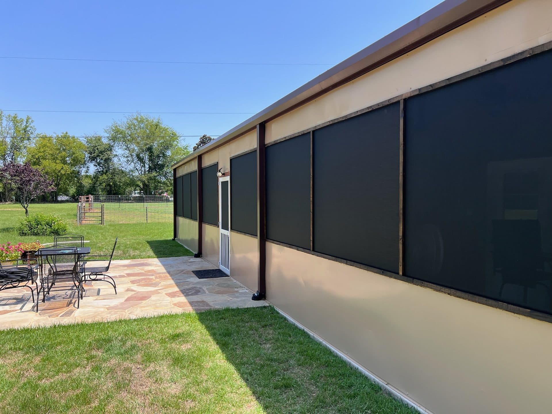 Screened sun porch exterior with solar shades and flagstone patio