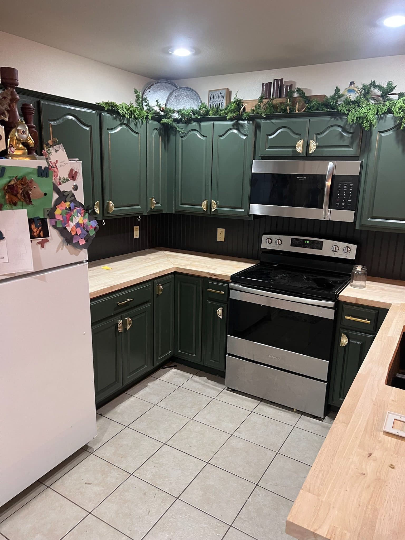 Hunter green kitchen range wall with stainless appliances and garland trim