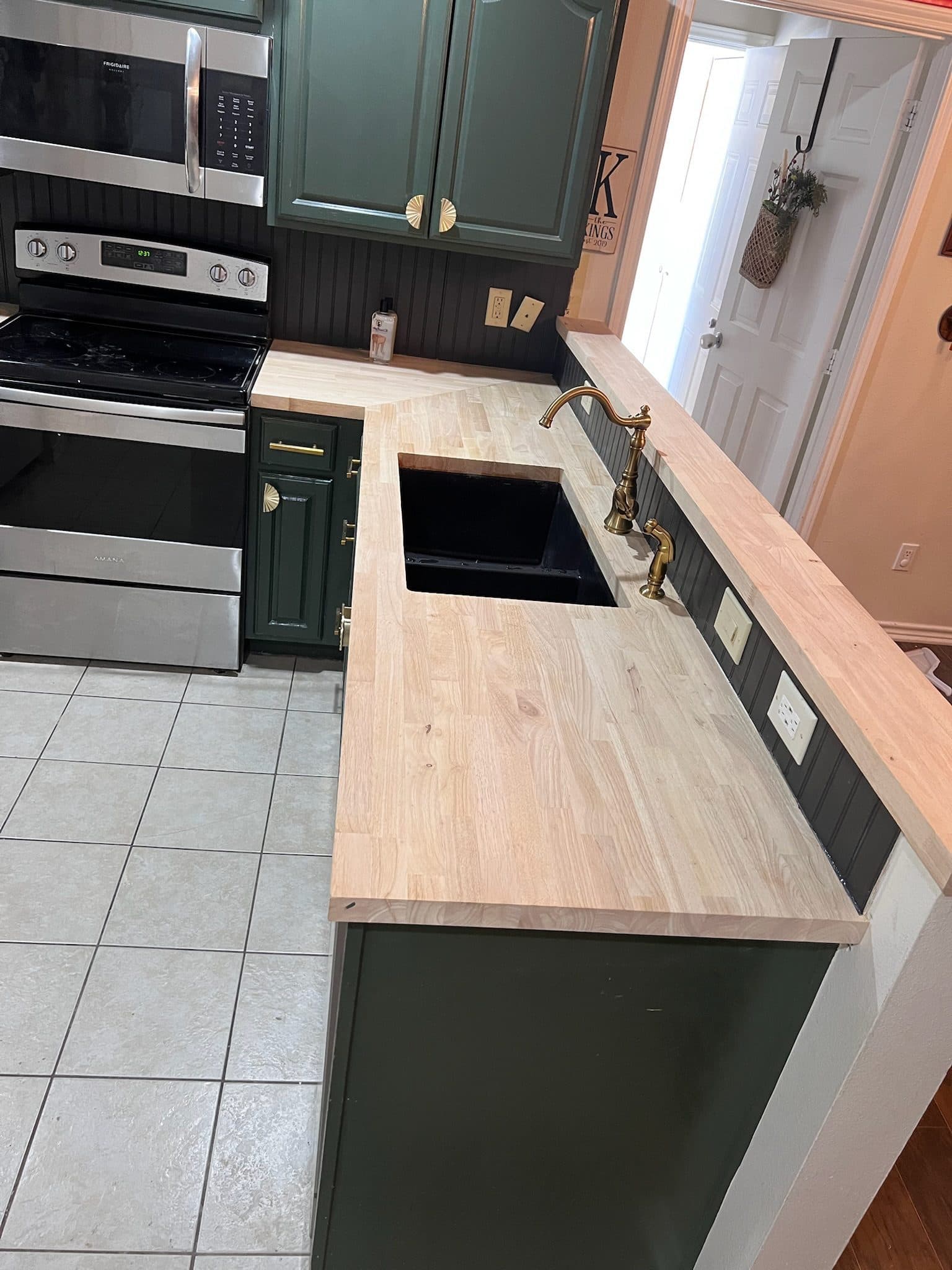Hunter green kitchen peninsula with butcher block and apron-front farmhouse sink
