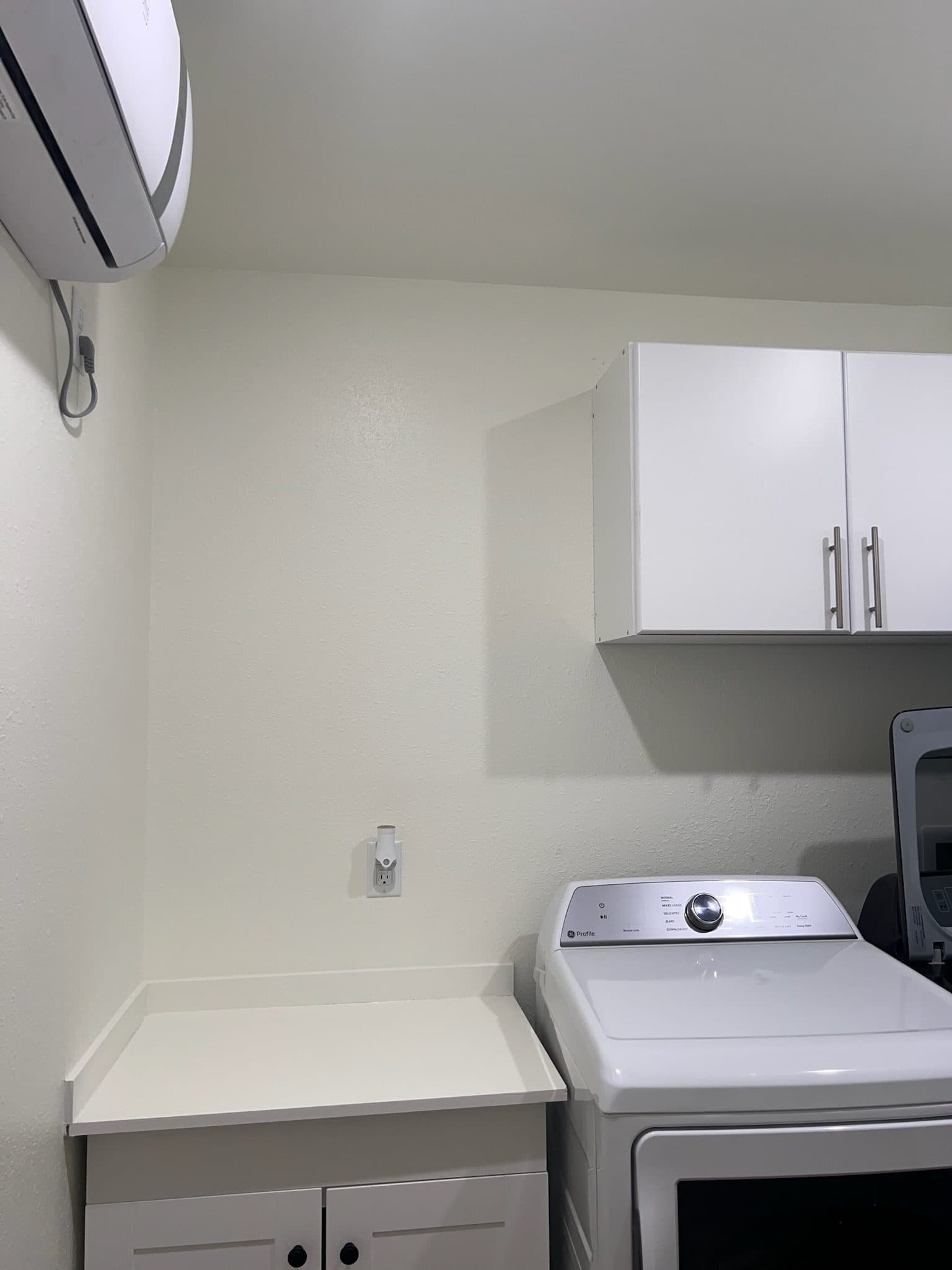 Laundry room with white upper cabinets over a washer and dryer