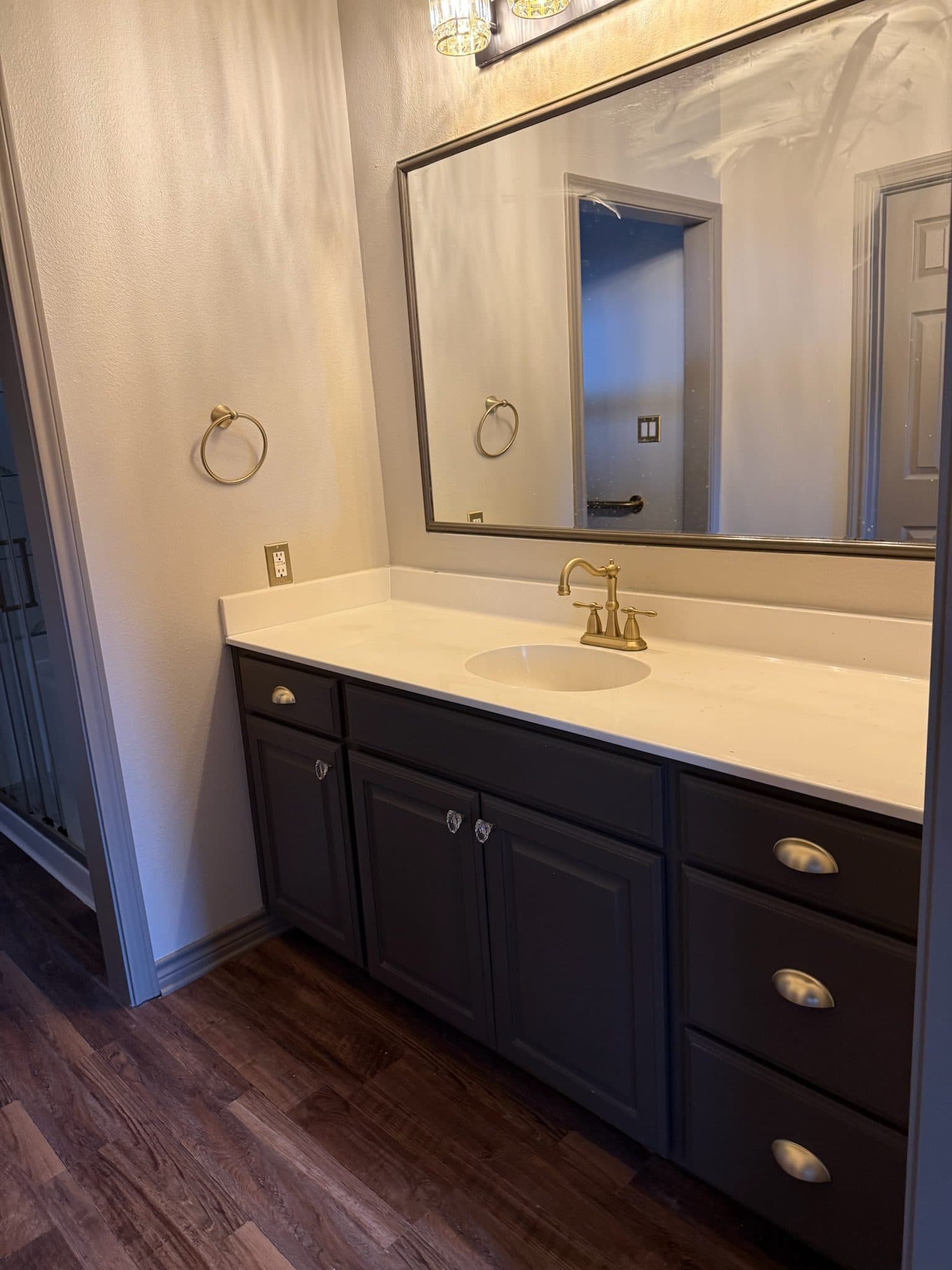 Primary bath dark wood vanity with gold faucet and large mirror