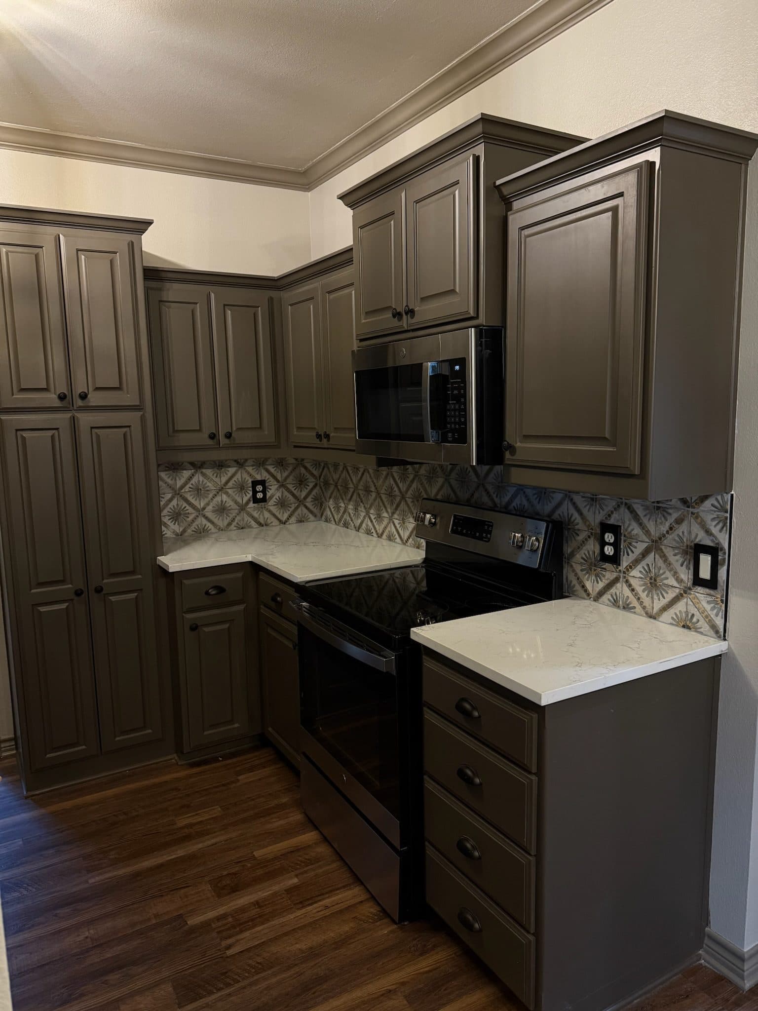 Wide view of taupe shaker kitchen with tile backsplash and oil-rubbed hardware