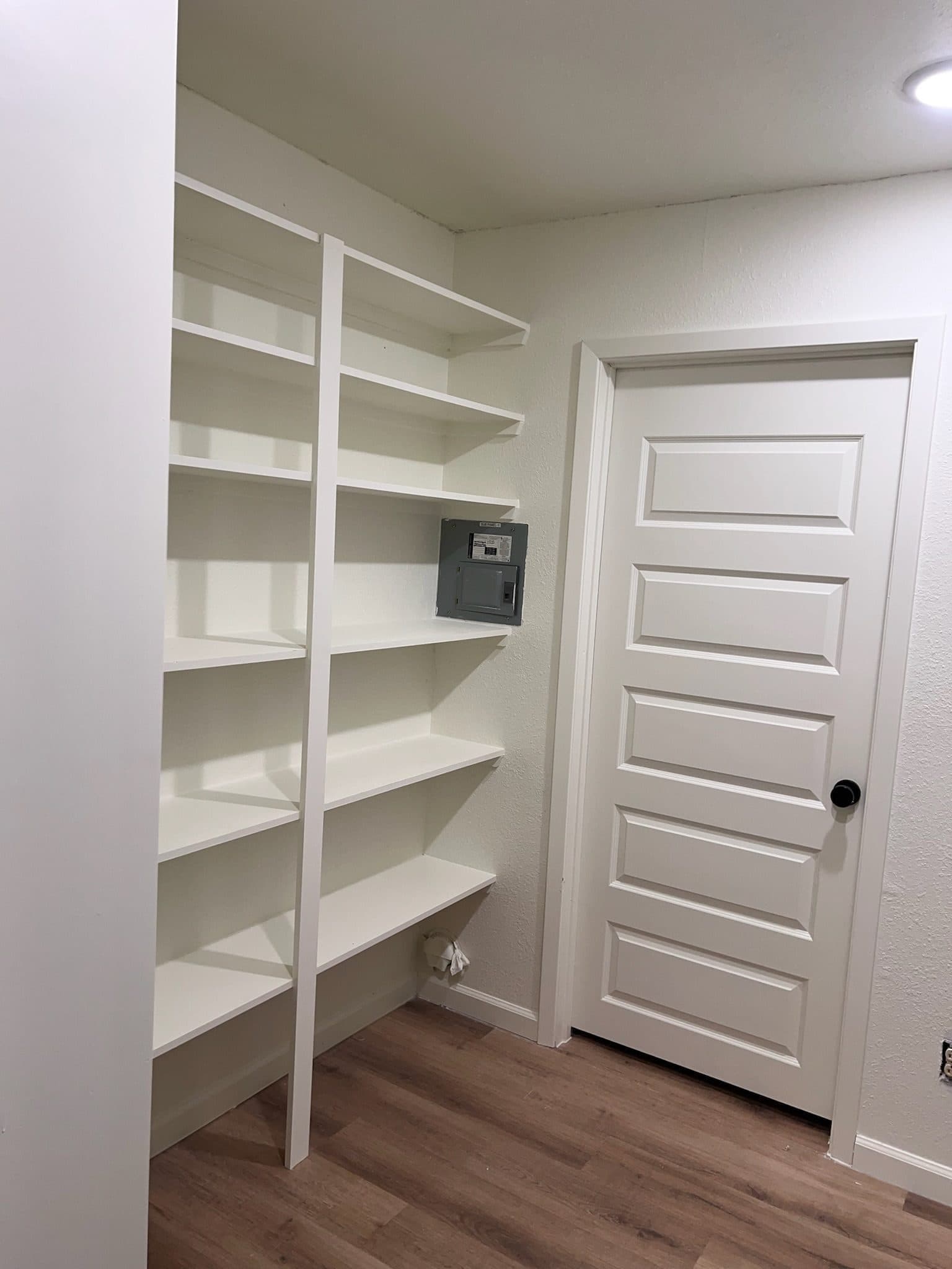 Walk-in pantry with 5-panel door and wood-look flooring