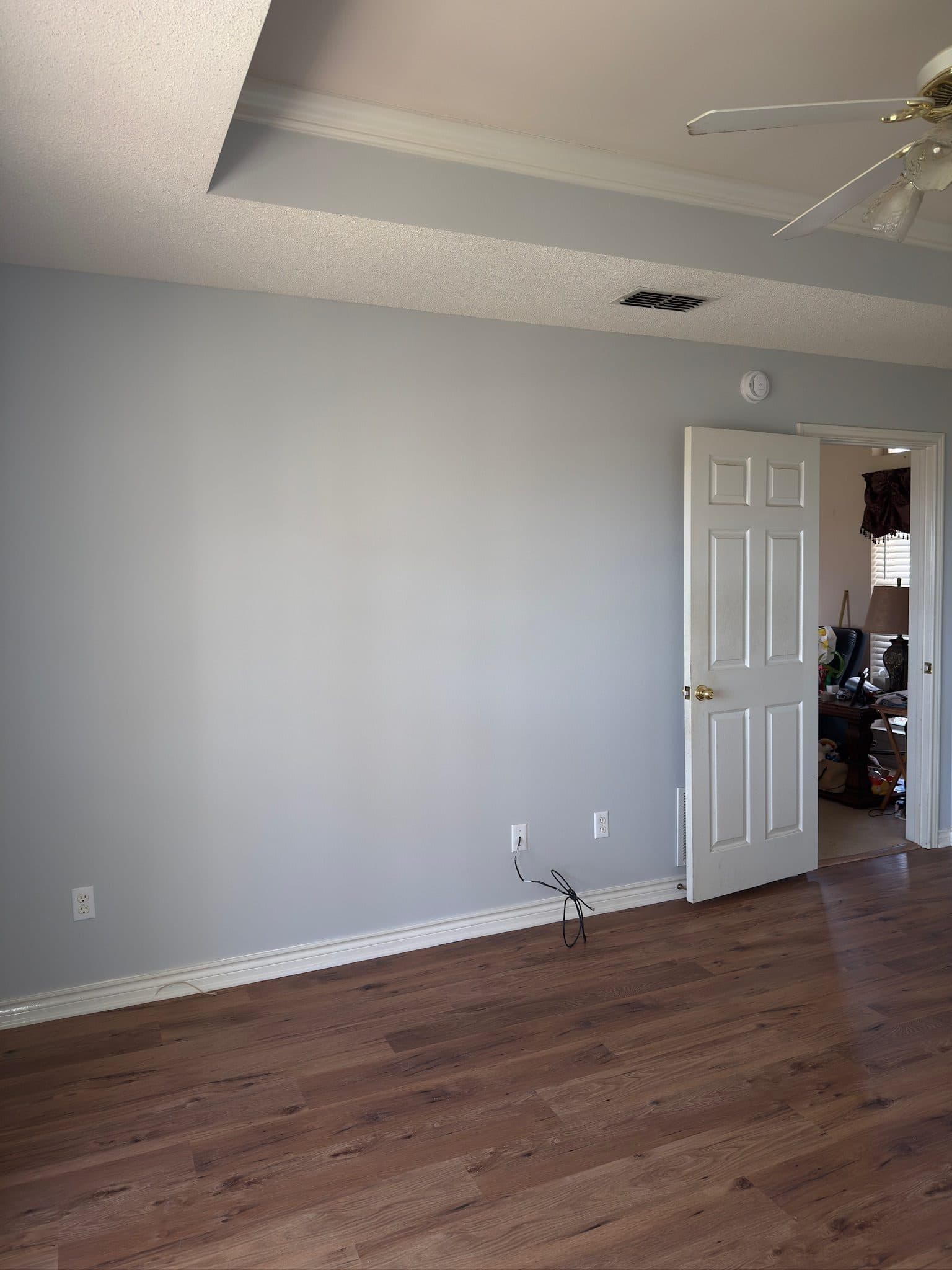 Grey painted bedroom with open door to adjoining office
