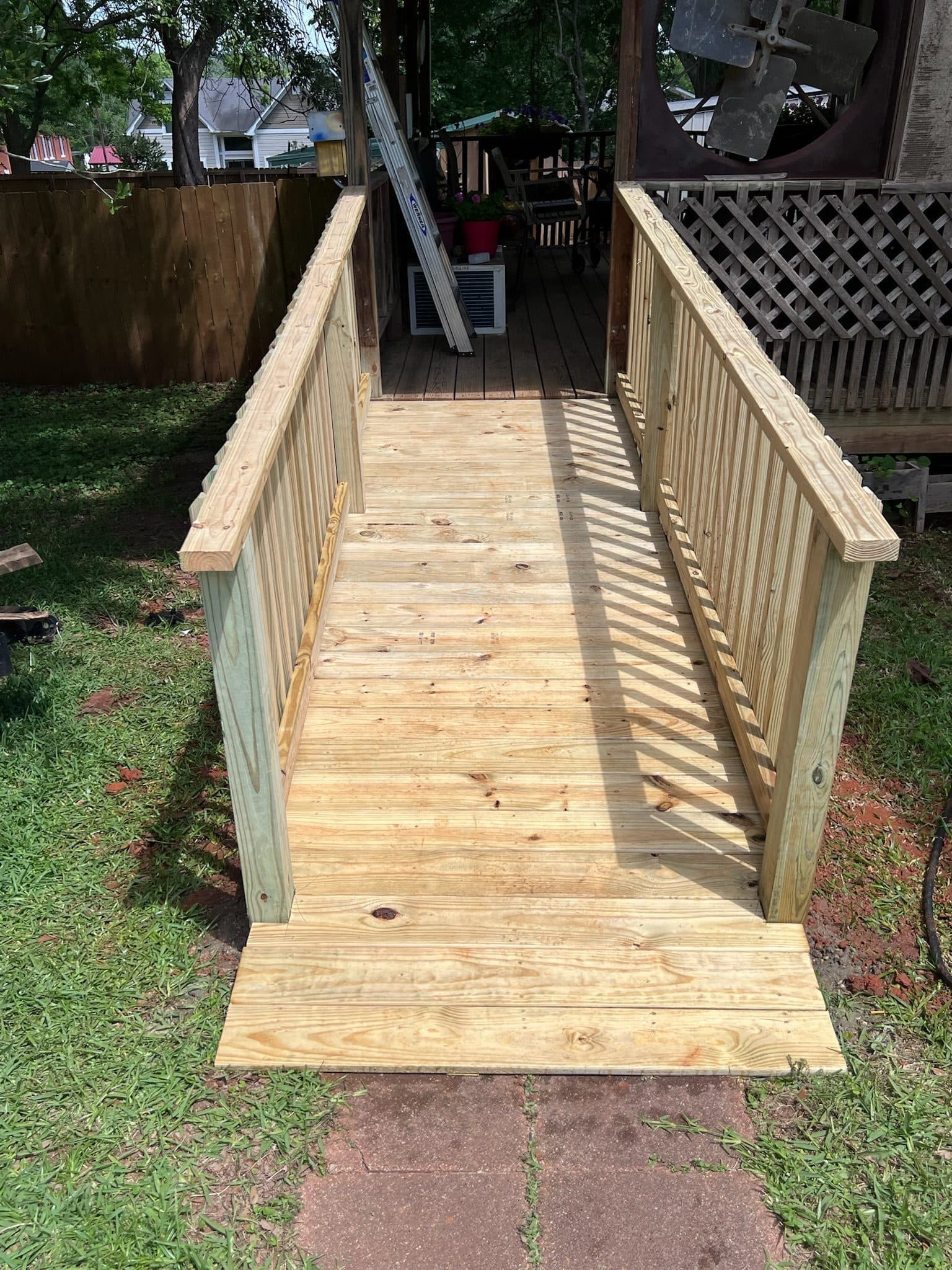 Pressure-treated ADA wood ramp with handrails to a backyard patio